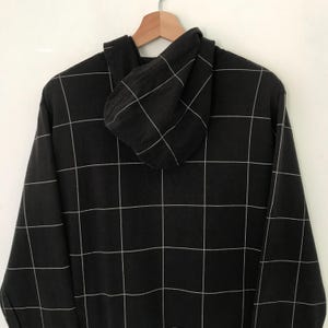 May include: Black hooded sweatshirt with a white grid pattern.