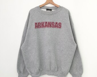 Può includere: Felpa grigia con una grafica rossa "ARKANSAS" sul davanti.
