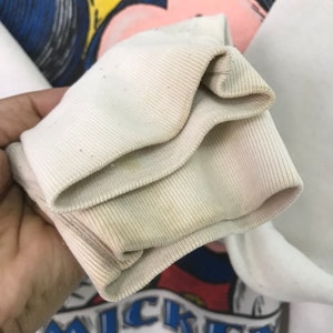 May include: Close-up of the white ribbed cuff of a sweatshirt. The cuff is folded over twice, showing the inside of the fabric.