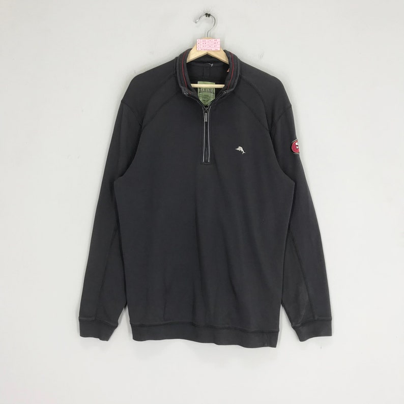 Peut inclure: Un sweat-shirt &agrave; manches longues noir avec une fermeture &eacute;clair quart et un petit logo de dauphin brod&eacute; sur la poitrine gauche et un patch plus grand sur la manche droite. Le patch pr&eacute;sente un logo rouge et blanc avec le texte "Original Penguin" en blanc.