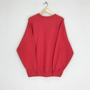 May include: A red long-sleeved sweatshirt with a crew neck.