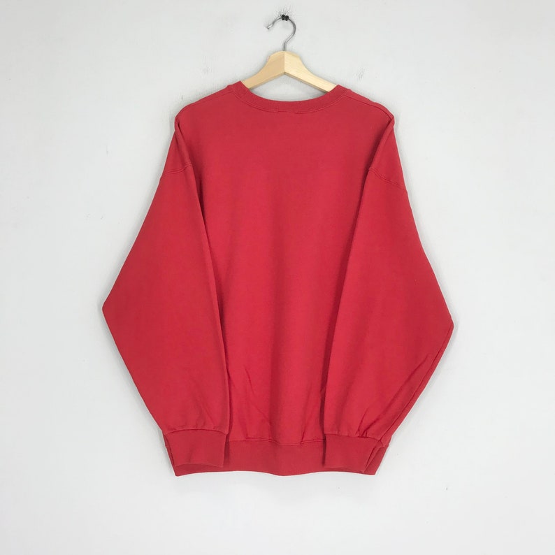May include: A red long-sleeved sweatshirt with a crew neck.