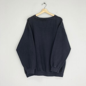 Puede incluir: Una sudadera de color azul marino oscuro con mangas largas y cuello redondo.