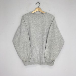 May include: A gray sweatshirt with long sleeves and a crew neck.