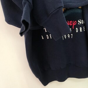 May include: A navy blue sweatshirt with a white graphic print that says "The Disney Store A Decade of Dreams 1997".