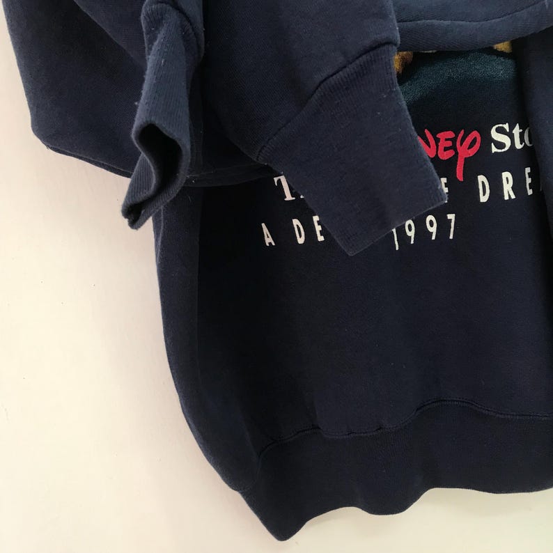 May include: A navy blue sweatshirt with a white graphic print that says "The Disney Store A Decade of Dreams 1997".