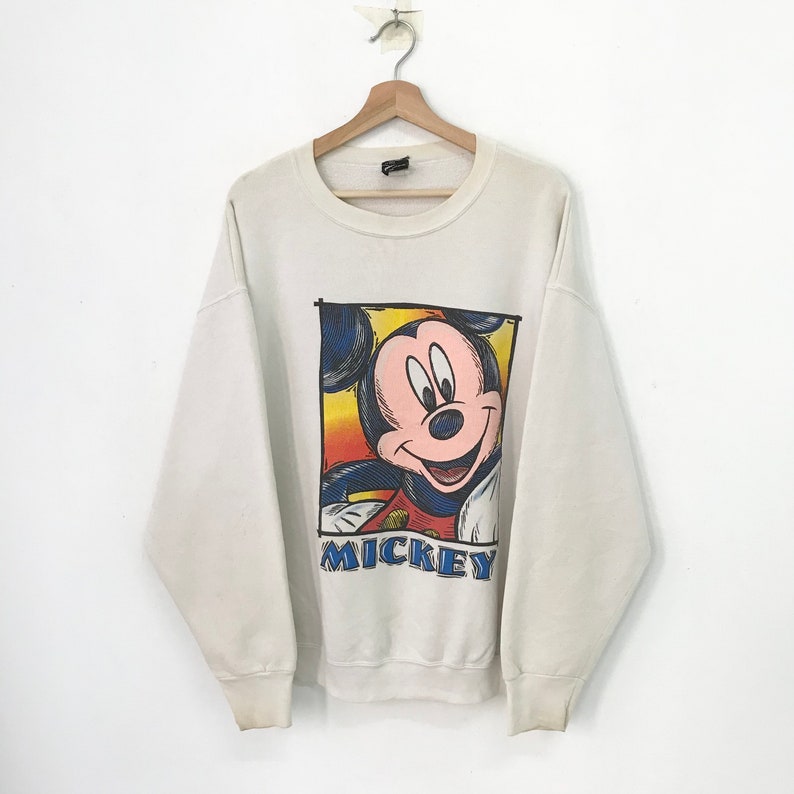May include: White sweatshirt with a colorful cartoon image of Mickey Mouse and the word "MICKEY" printed on the front.