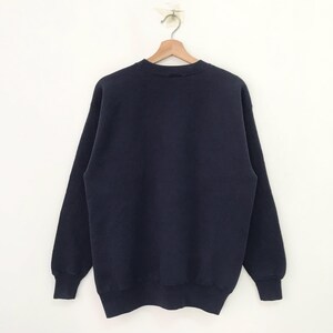 May include: A dark blue sweatshirt with long sleeves and a crew neck.