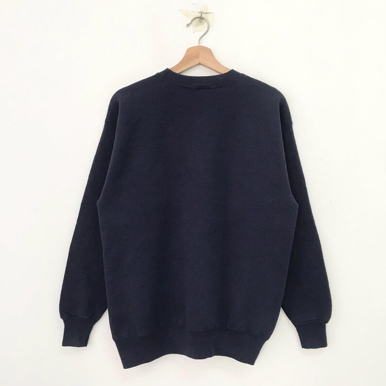 May include: A dark blue sweatshirt with long sleeves and a crew neck.