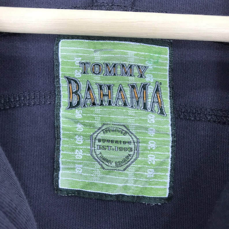 Peut inclure: Une &eacute;tiquette verte et blanche avec le texte "TOMMY BAHAMA" en noir et le texte "BUNGALOW EST. 1993" en plus petit.