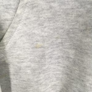 Puede incluir: Una prenda de tela jaspeada gris claro con una costura diagonal visible y una peque&ntilde;a mancha amarillenta tenue situada cerca del centro del material texturizado, mostrando claramente el tejido del textil en esta vista de primer plano.