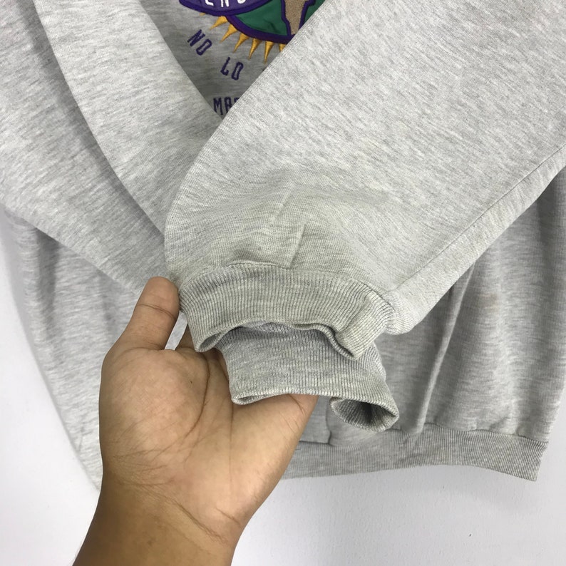 May include: Gray sweatshirt with a graphic of a globe and the text "No Limits" on the front. The sweatshirt has a ribbed cuff and hem.