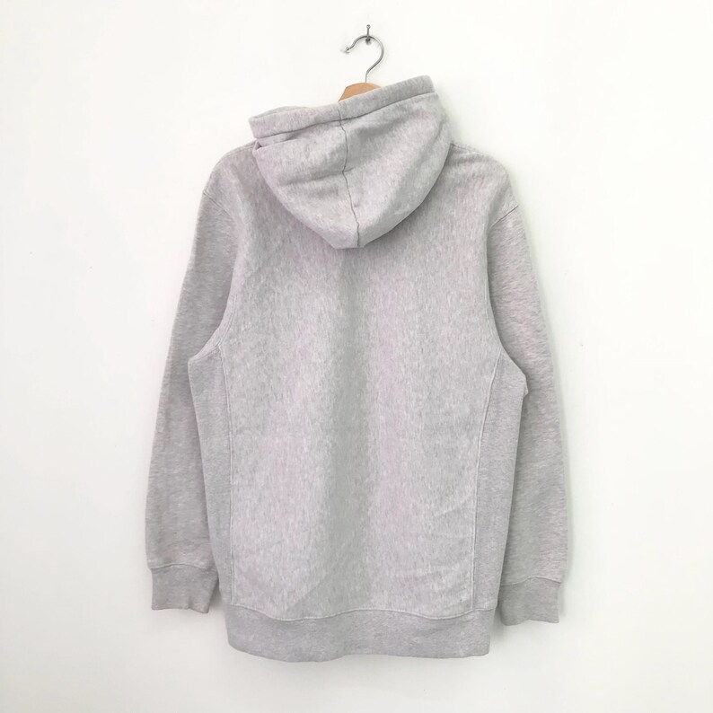 May include: A gray hooded sweatshirt with a drawstring hood. The sweatshirt has long sleeves and a kangaroo pocket.