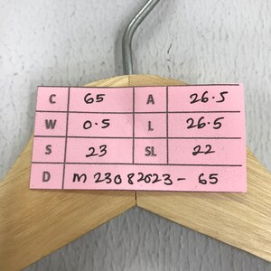 Puede incluir: Una nota adhesiva rosa con una cuadr&iacute;cula de letras y n&uacute;meros. Las letras son C, W, S y D. Los n&uacute;meros son 65, 0.5, 23 y m 230 82023-65. Las letras A, L y SL tambi&eacute;n est&aacute;n presentes con los n&uacute;meros 26.5, 26.5 y 22.