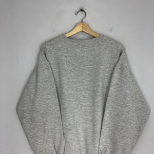 May include: A gray sweatshirt with long sleeves and a crew neck.