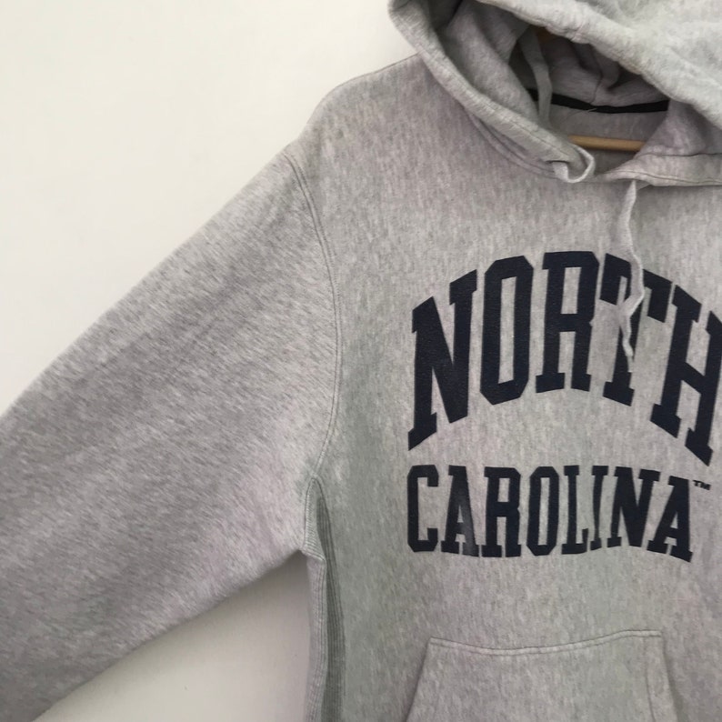 May include: Gray hooded sweatshirt with a navy blue "NORTH CAROLINA" logo printed on the front.