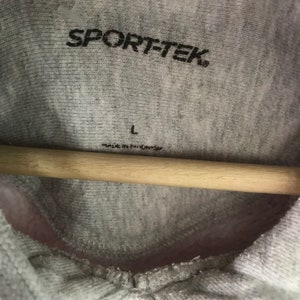 May include: Gray hooded sweatshirt with the text "SPORT-TEK" and a size label that says "L" and "Made in China".