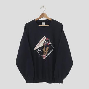 May include: Navy blue sweatshirt featuring a diamond-shaped graphic with the text "Kentucky Derby 129". The graphic includes a horse and jockey, a rose, and the words "Churchill Downs".