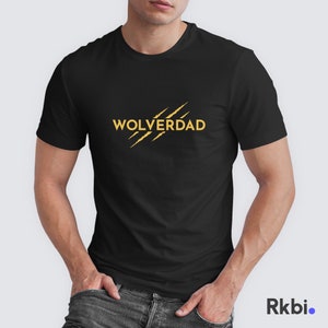 May include: Black t-shirt featuring the gold text "Wolverdad" and three gold claw marks. The shirt has a crew neck and short sleeves.