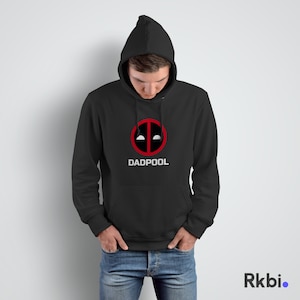 Può includere: Felpa con cappuccio nera con un logo Deadpool rosso e bianco e il testo "DADPOOL" stampato sul davanti.