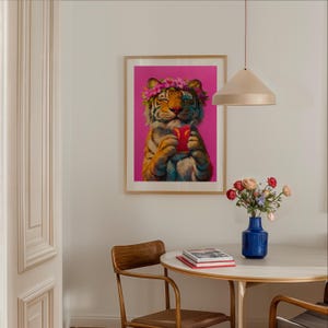 May include: A framed wall art print featuring a tiger with a pink flower crown, holding a red drink with a slice of citrus. The tiger has its eyes closed and is set against a vibrant magenta background, displayed in a light wood frame.
