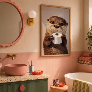 May include: A framed wall art print featuring a brown otter holding a roll of white toilet paper. The artwork is displayed in a bathroom with a pink scalloped mirror, a pink vessel sink, a green vanity, and a white bathtub with a green wavy towel.