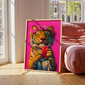 May include: A framed art print featuring a tiger with a flower crown on its head, holding a glass of pink liquid with orange slices. The tiger has orange and black stripes, and the background of the artwork is a vibrant, solid hot pink color.
