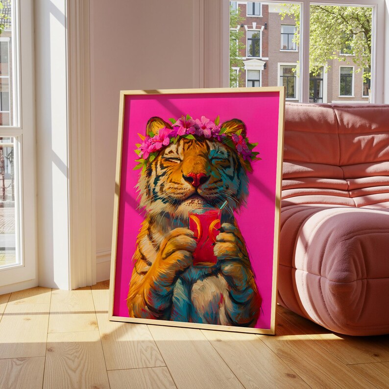May include: A framed art print featuring a tiger with a flower crown on its head, holding a glass of pink liquid with orange slices. The tiger has orange and black stripes, and the background of the artwork is a vibrant, solid hot pink color.