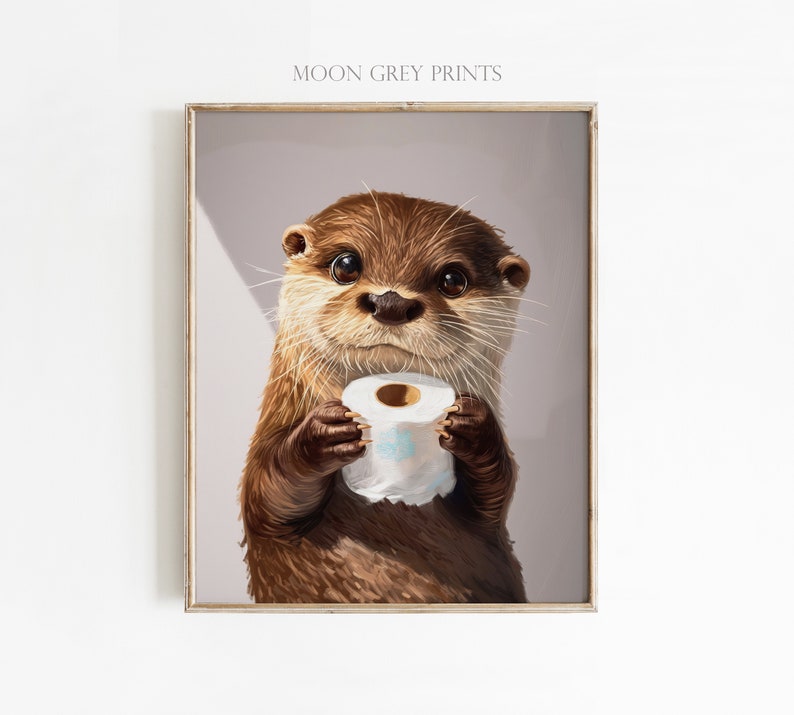 May include: A framed wall art print featuring a brown otter with large dark eyes holding a roll of white toilet paper. The text MOON GREY PRINTS is visible at the top of the print. The otter has detailed fur texture and whiskers against a light gray background.