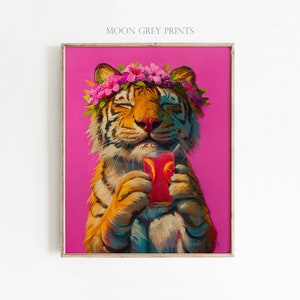 May include: A framed art print titled MOON GREY PRINTS featuring an orange and black tiger with closed eyes wearing a pink hibiscus flower crown. The tiger holds a glass of red liquid with orange slices against a solid bright pink background.