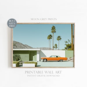 Pode incluir: Um carro laranja vintage estacionado em frente a uma casa moderna de meados do século com uma parede de azulejos verdes. Palmeiras margeiam a entrada. A imagem é emoldurada em uma moldura de madeira clara. "MOON GREY PRINTS" e "PRINTABLE WALL ART INSTANT DIGITAL DOWNLOAD" estão impressos abaixo da imagem.