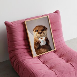 May include: A framed wall art print featuring a brown otter holding a white roll of toilet paper. The otter has dark eyes, a wet nose, and light-colored whiskers. The artwork is enclosed in a light-colored wooden frame with a simple, clean edge.