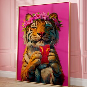 May include: A framed wall art print featuring an orange and black tiger with closed eyes, wearing a crown of pink hibiscus flowers and green leaves. The tiger holds a glass of red liquid with orange slices and a straw against a bright pink background.