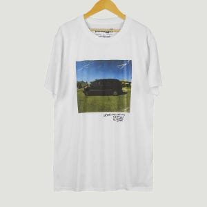 May include: White t-shirt featuring a graphic of a black van on grass under a blue sky. The image has a vintage, distressed appearance. Text at the bottom reads "GOOD KID, M.A.A.D CITY, A SHORT FILM BY KENDRICK LAMAR."