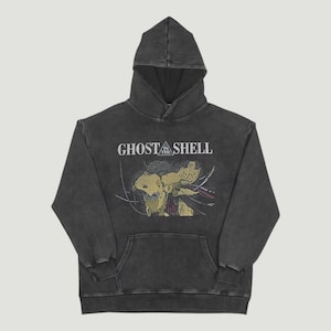 Peut inclure: Sweat à capuche gris foncé avec le texte "GHOST IN THE SHELL" et une illustration graphique. Le sweat à capuche a une capuche à cordon et une poche kangourou. Le design est en jaune, rouge et blanc.
