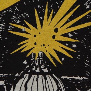 May include: A black fabric featuring a graphic print of a large, yellow, multi-pointed starburst shape positioned above a white, dome-like structure. The design includes scattered white dots against the black background, creating a celestial effect.