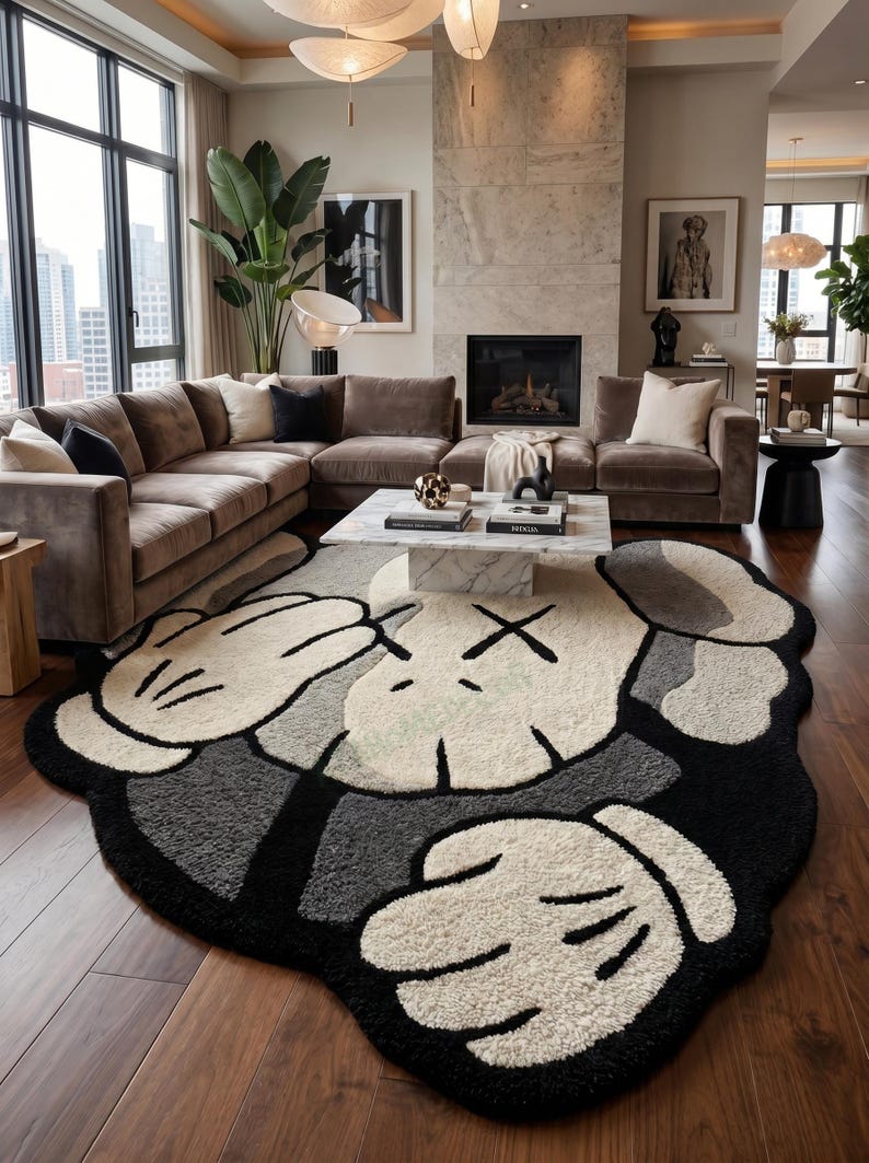 May include: A large, plush rug with a cartoon character design in a living room setting. The rug features a white, black, and gray color scheme, with a distinctive character face and hand motif. The rug is placed on a hardwood floor.