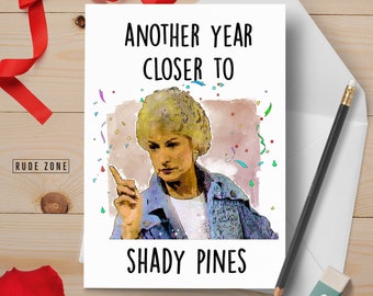 May include: A white card with a colourful image of a woman with blonde hair and the text "Another year closer to Shady Pines".