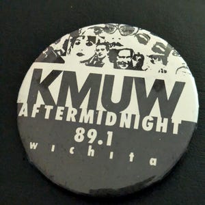 May include: A circular pinback button featuring a black and white graphic design. The top section displays a collage of faces, while the center text reads KMUW AFTERMIDNIGHT. Below this, the text 89.1 and the word wichita are printed in white.