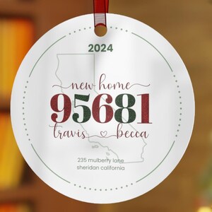May include: A white round Christmas ornament with a red ribbon. The ornament features the text "new home" and the address "235 mulberry lane sheridan california". The year "2024" is also displayed.