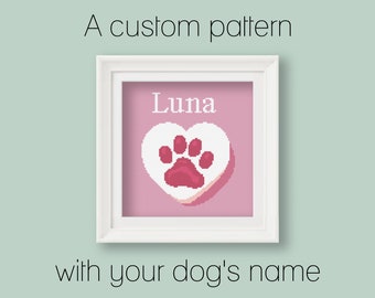 May include: A white frame with a pink background and a white heart with a pink paw print inside. The name "Luna" is written above the heart. A custom pattern with your dog's name.