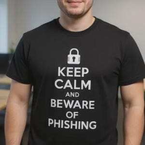 Pode incluir: Uma camiseta preta com o texto branco "KEEP CALM AND BEWARE OF PHISHING". A camiseta apresenta um cadeado acima do texto. A pessoa está usando um relógio preto.