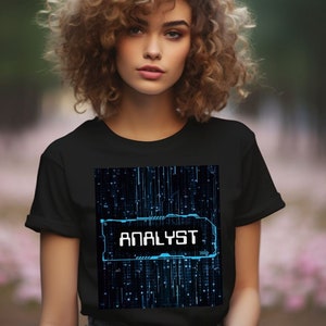 Könnte beinhalten: Ein schwarzes T-Shirt mit einem blauen und schwarzen Grafikdesign, das das Wort "ANALYST" auf einem digitalen Hintergrund zeigt.