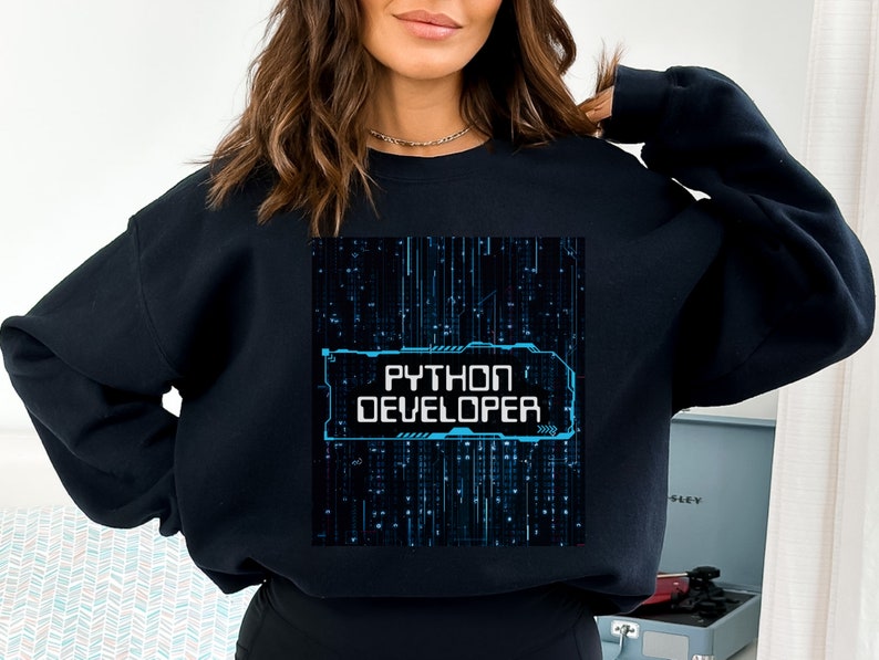 K&ouml;nnte beinhalten: Schwarzes Sweatshirt mit einem blauen und wei&szlig;en Grafikdesign, auf dem "Python Developer" auf einem schwarzen Hintergrund mit blauen Linien steht.