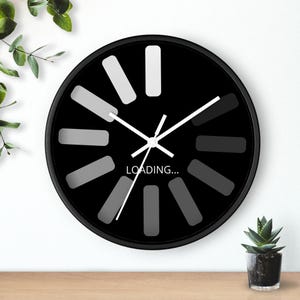 May include: A black round wall clock with white hands and a loading bar design. The clock face has a black background with white numbers and the text "LOADING..." in the centre.
