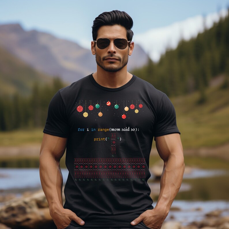 以下が含まれることがあります： カラフルなオーナメントと「for i in range(mom said so): print('')」というコードでできたクリスマスツリーのデザインが施された黒いTシャツ。