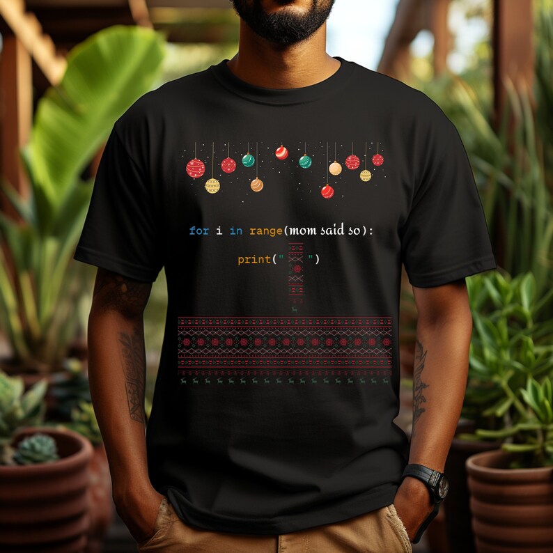 以下が含まれることがあります： コード「for i in range(mom said so): print('')」と、その上に吊るされたカラフルなオーナメントの列が描かれた、黒いTシャツ。クリスマスをテーマにしたデザインです。