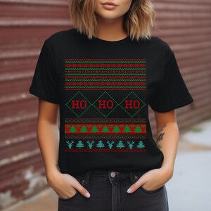 May include: Black t-shirt with a red and green Christmas-themed design. The design features a repeating pattern of snowflakes, trees, reindeer, and the words "HO HO HO" in a diamond shape.