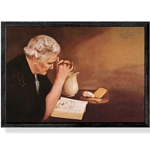 May include: A framed print depicting an elderly person with white hair, hands clasped in prayer, and eyes closed. A Bible, eyeglasses, a pitcher, and bread are on the table. The artwork has a warm, sepia-toned color palette.