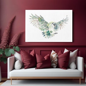 K&ouml;nnte beinhalten: Ein Aquarellbild eines Eulen mit ausgebreiteten Fl&uuml;geln. Die Eule ist in Gr&uuml;n-, Braun- und Wei&szlig;t&ouml;nen dargestellt und vor einem wei&szlig;en Hintergrund platziert. Das Bild ist in einem wei&szlig;en Rahmen gerahmt und h&auml;ngt an einer burgunderfarbenen Wand.